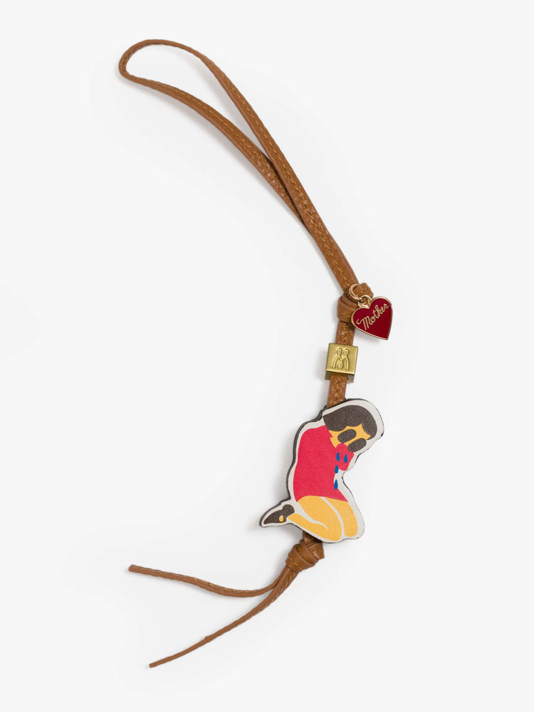 A tan bag charm made from 100% leather with a heart charm, M bead and a 1.8 x 1.4-inch crying girl at the end.