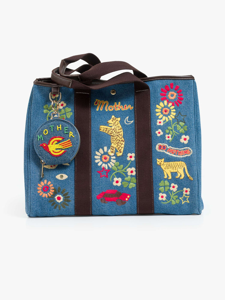 Flat view of a Tote is designed in mid blue denim with brown top handles, colorful embroidery and MOTHER embroidered across the front in yellow and red.