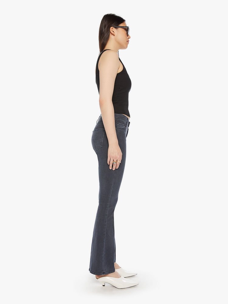 Side view of a womens mid rise flare jean in a faded black wash and clean hem.
