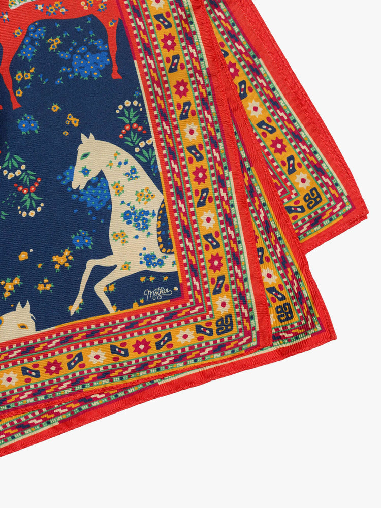 Flat view square scarf made from 100% silk in navy blue with a folk art-inspired horse print and orange trim.