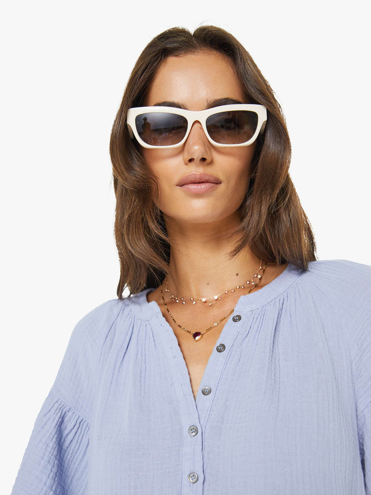 Close up view of a woman in a light lavender with a deep V-neck, ruffled short sleeves and a loose, flowy fit.