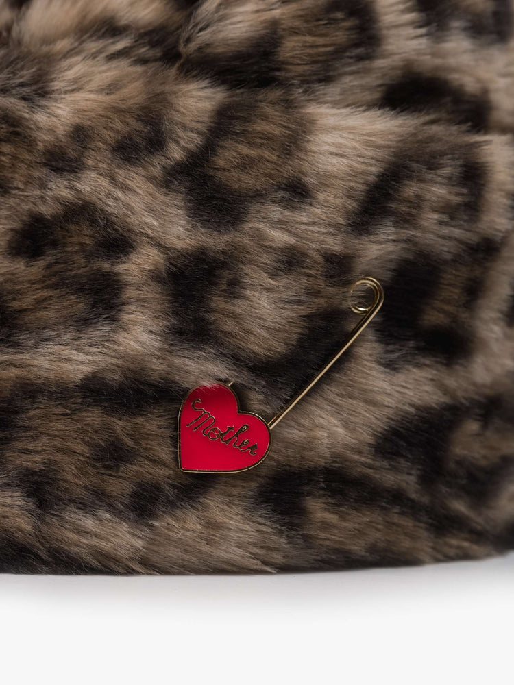 Flat of a hat with a wide folded brim and a decorative gold-toned pin with a red heart.
