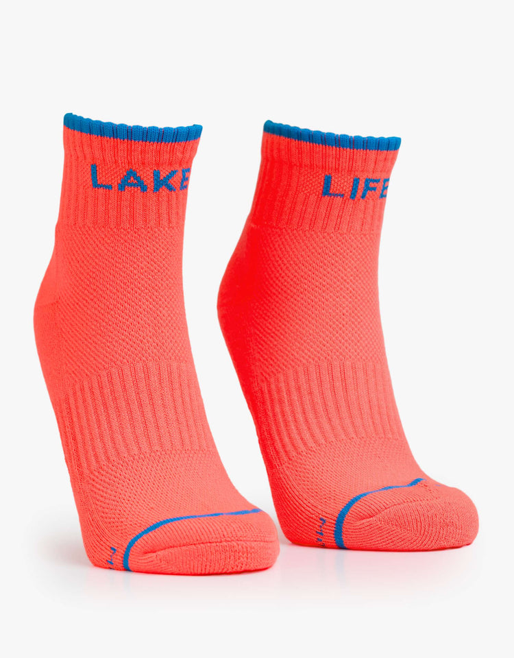 Flats view ankle-length tube socks designed in neon orange with blue text and details.