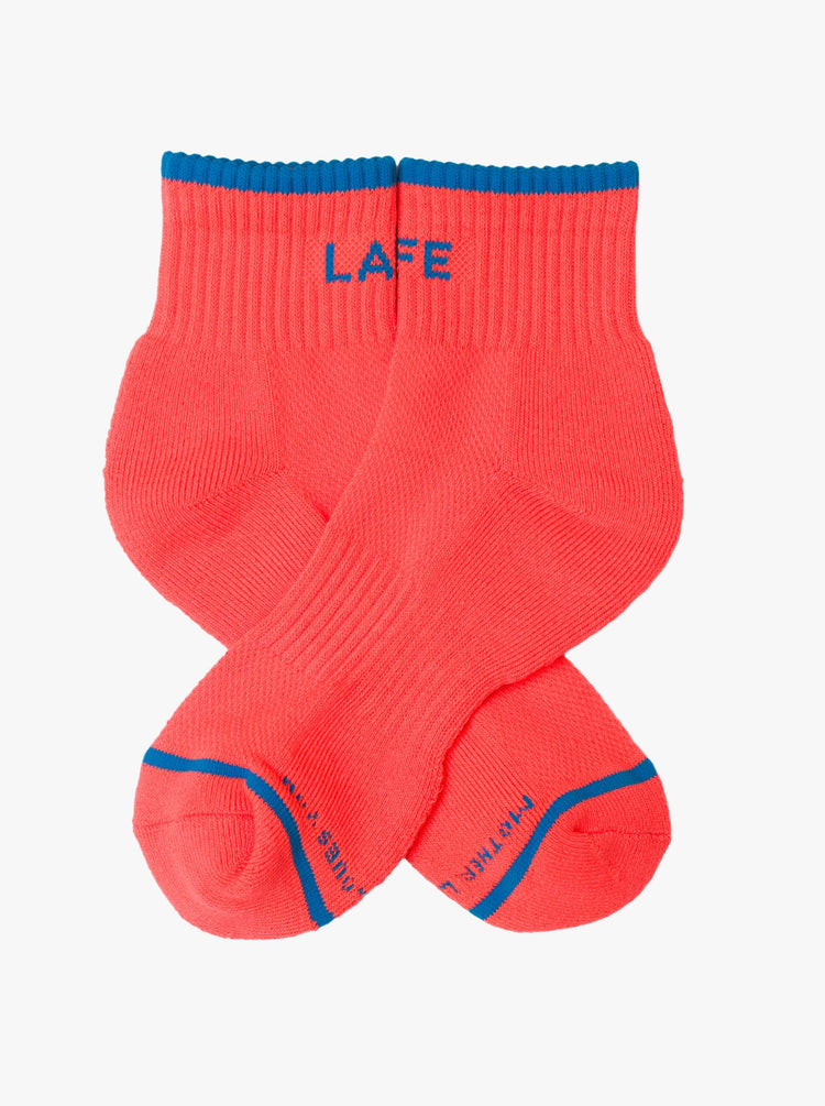 Flat view ankle-length tube socks designed in neon orange with blue text and details.
