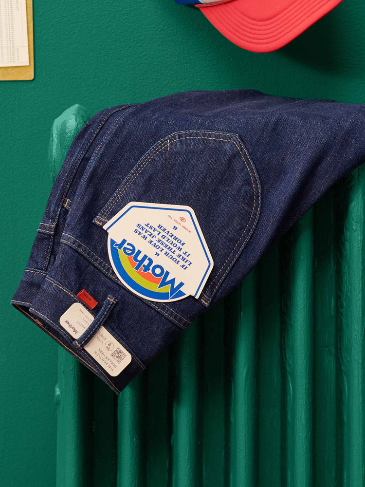 Lost & Found editorial image of a pair a dark blue jeans draped over a green radiator against a green wall.