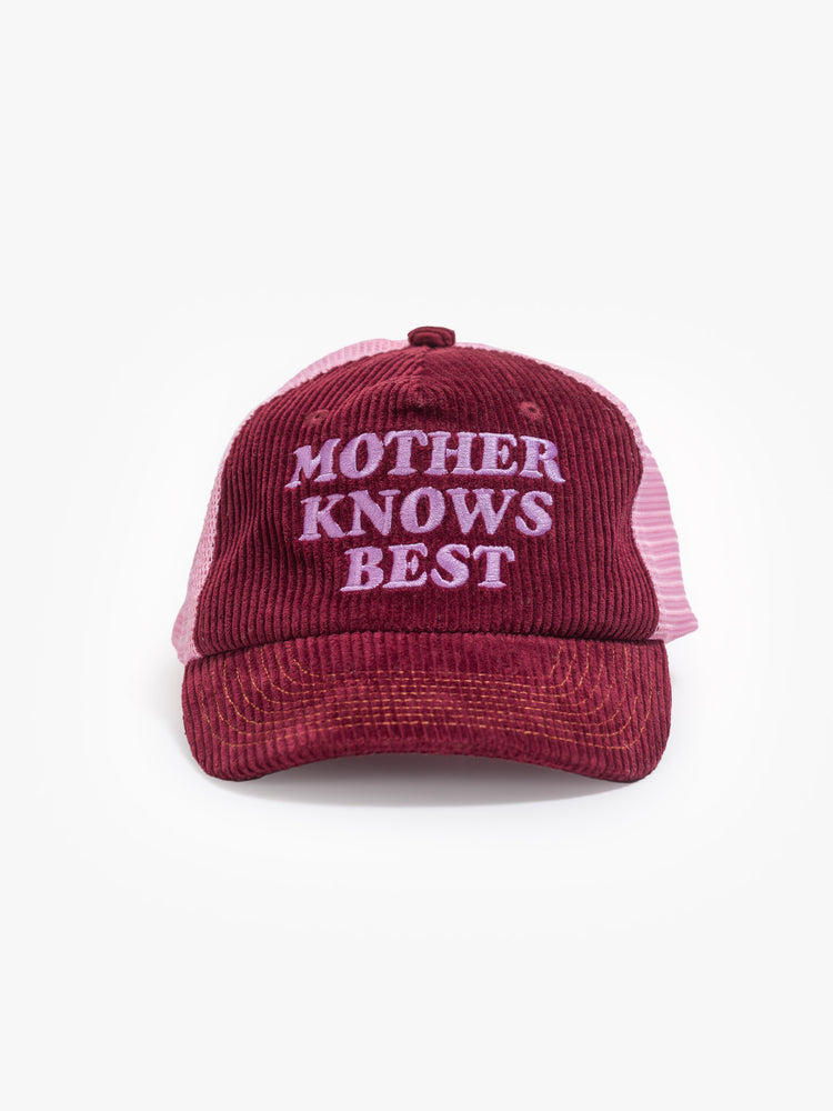Front view of a vintage-inspired trucker hat in a maroon-colored corduroy with embroidered text on the front, pink mesh in the back and three statement-making pins.