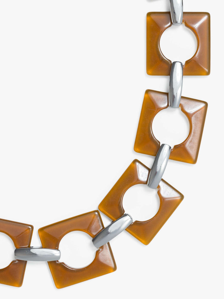 Close up chunky belt featuring brown square and circular resin pieces connected by metal links.