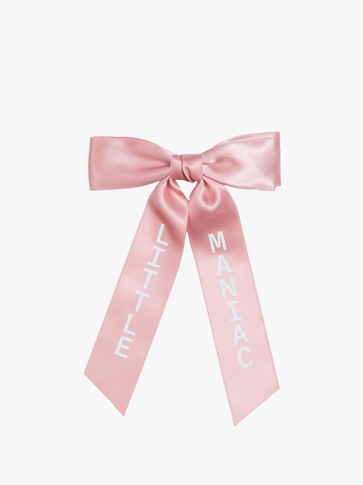 Flat view of a pink, satin-feel hair bow that looks sweet but says otherwise—with LITTLE on one tail and MANIAC on the other.