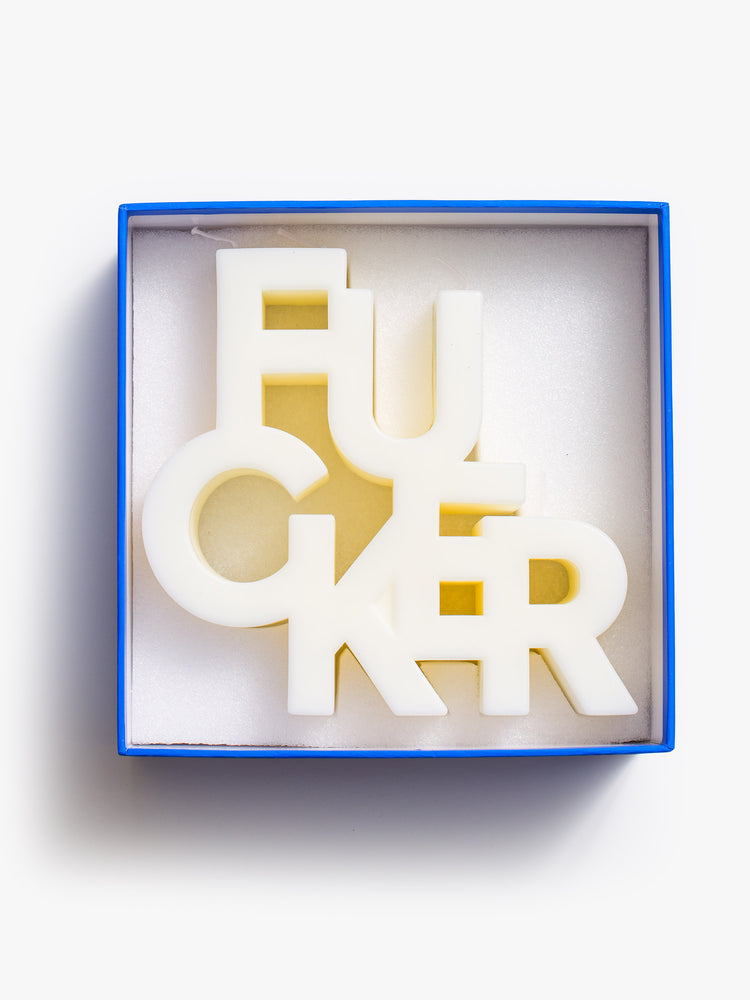 Image of an off white candle made up of stacked letters reading "FUCKER", inside a blue box..
