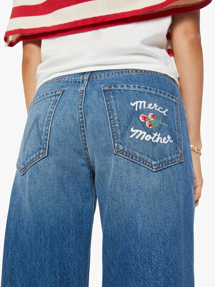 Close up view of a woman in a medium blue wide-leg jeans are designed to sit lower on the hips with a zip fly and a clean ankle-length inseam. 