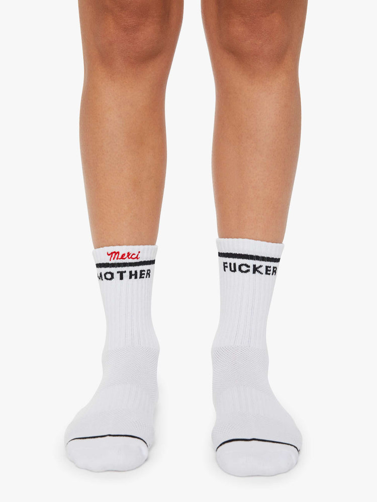 On model wearing white with bold lettering in black socks and "Merci" embroidered in red at the hem. 