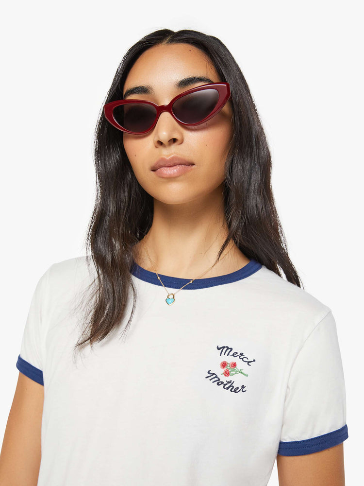 Close up view of a woman in a short sleeve tee is made from 100% supima cotton in white with navy trim, and features embroidered text in navy and a small bouquet on the chest.