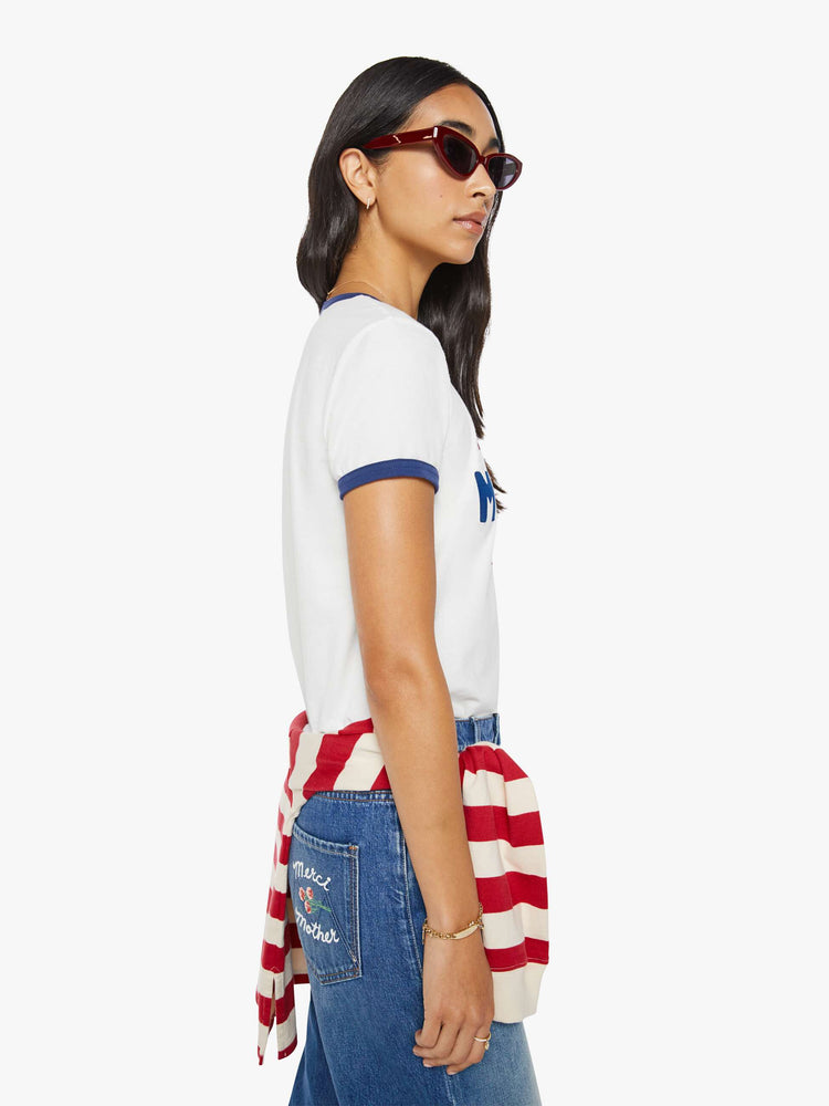 Side view of a woman in a short sleeve tee is made from 100% supima cotton in white with navy trim, and features an oversized text graphic in red and blue on the front.