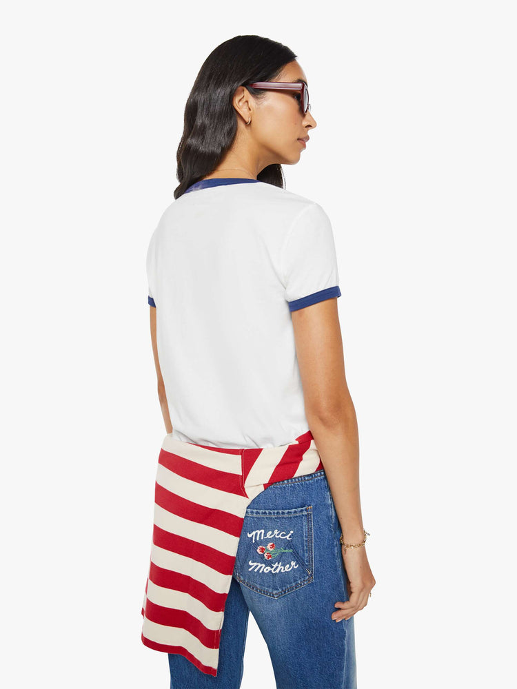 Back view of a woman in a short sleeve tee is made from 100% supima cotton in white with navy trim, and features an oversized text graphic in red and blue on the front.