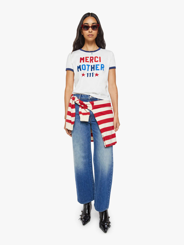 Full body view of a woman in a short sleeve tee is made from 100% supima cotton in white with navy trim, and features an oversized text graphic in red and blue on the front.