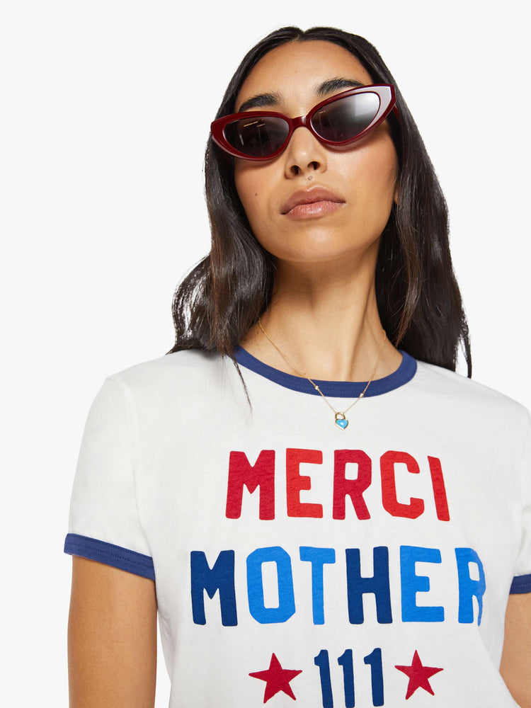 Close up view of a woman in a short sleeve tee is made from 100% supima cotton in white with navy trim, and features an oversized text graphic in red and blue on the front.