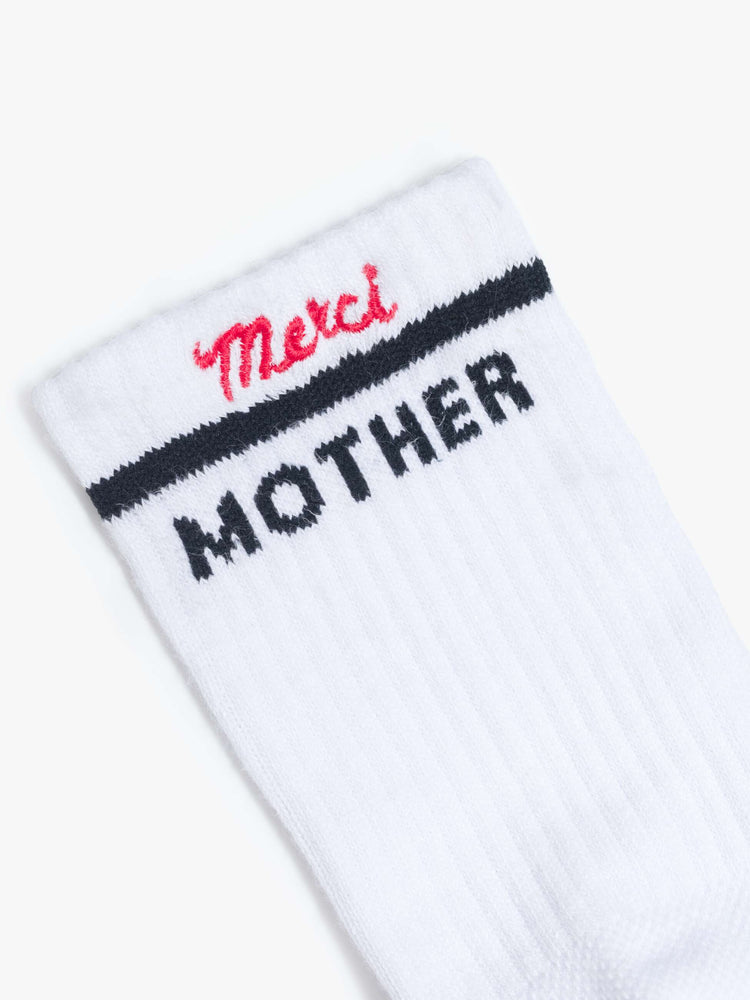 Close up view of white with bold lettering in black socks and "Merci" embroidered in red at the hem. 