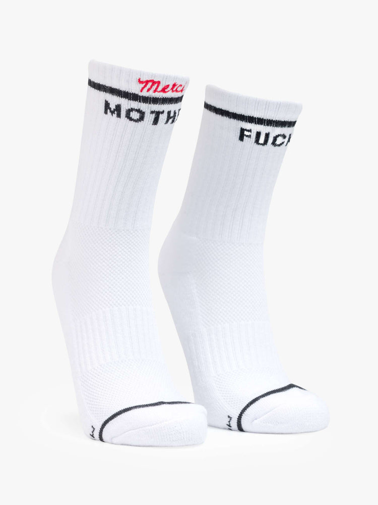 Flat view of white with bold lettering in black socks and "Merci" embroidered in red at the hem. 
