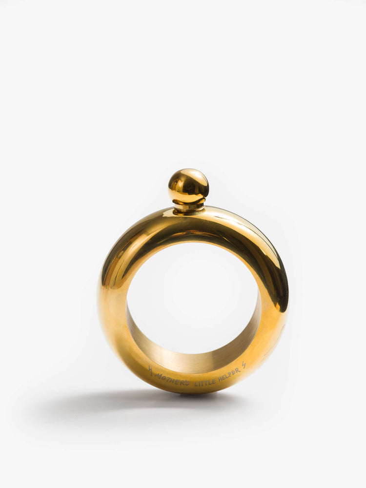 A Brass-toned flask is designed with a rounded twist-on lid and a cheeky engraved message across the base.