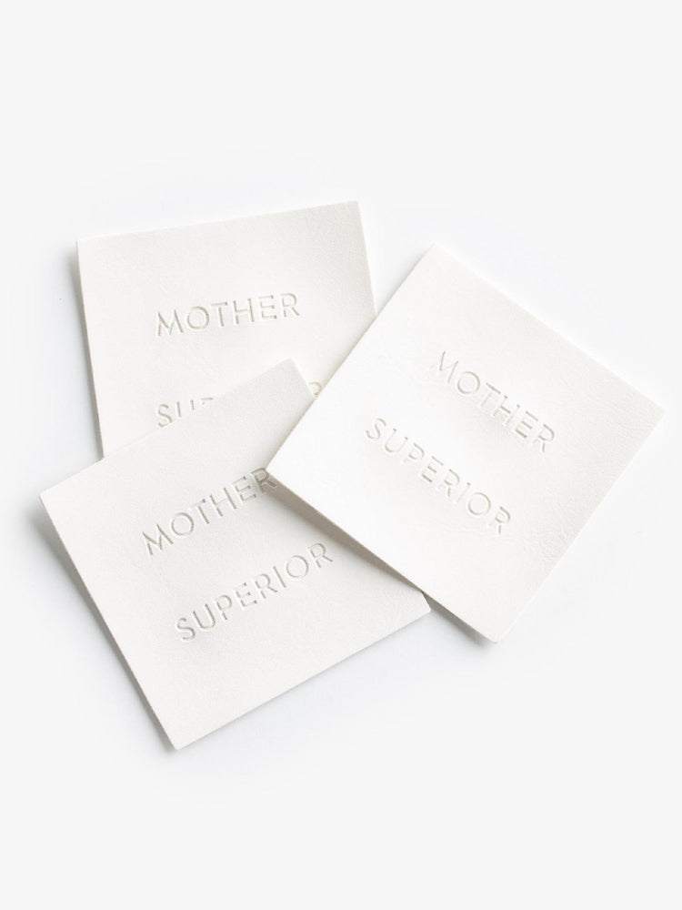 A pile of of white square MOTHER SUPERIOR labels.