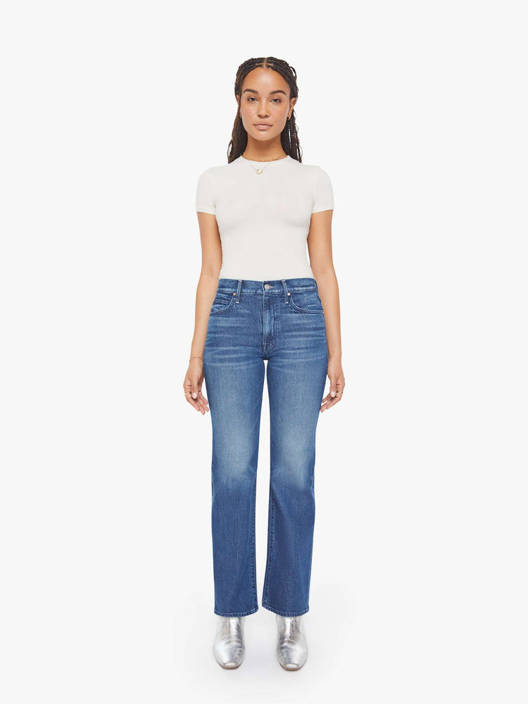 Front view of a petite woman in mid blue high-rise straight leg jean with a zip fly, long 30-inch inseam and a clean hem.