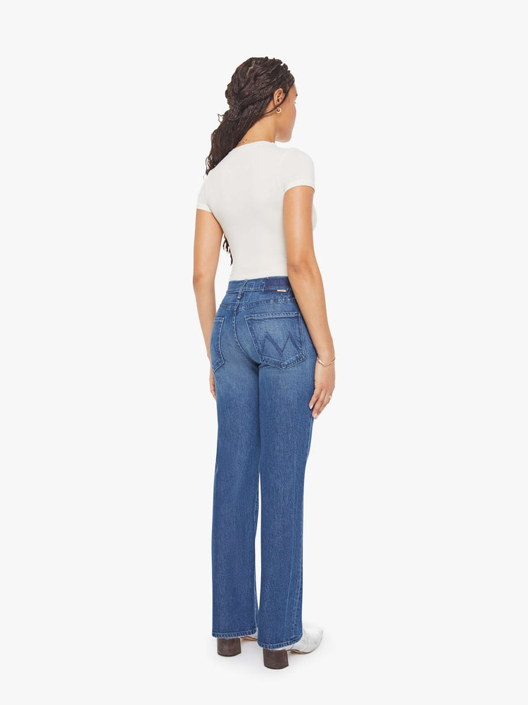 Back view of a petite woman in mid blue high-rise straight leg jean with a zip fly, long 30-inch inseam and a clean hem.