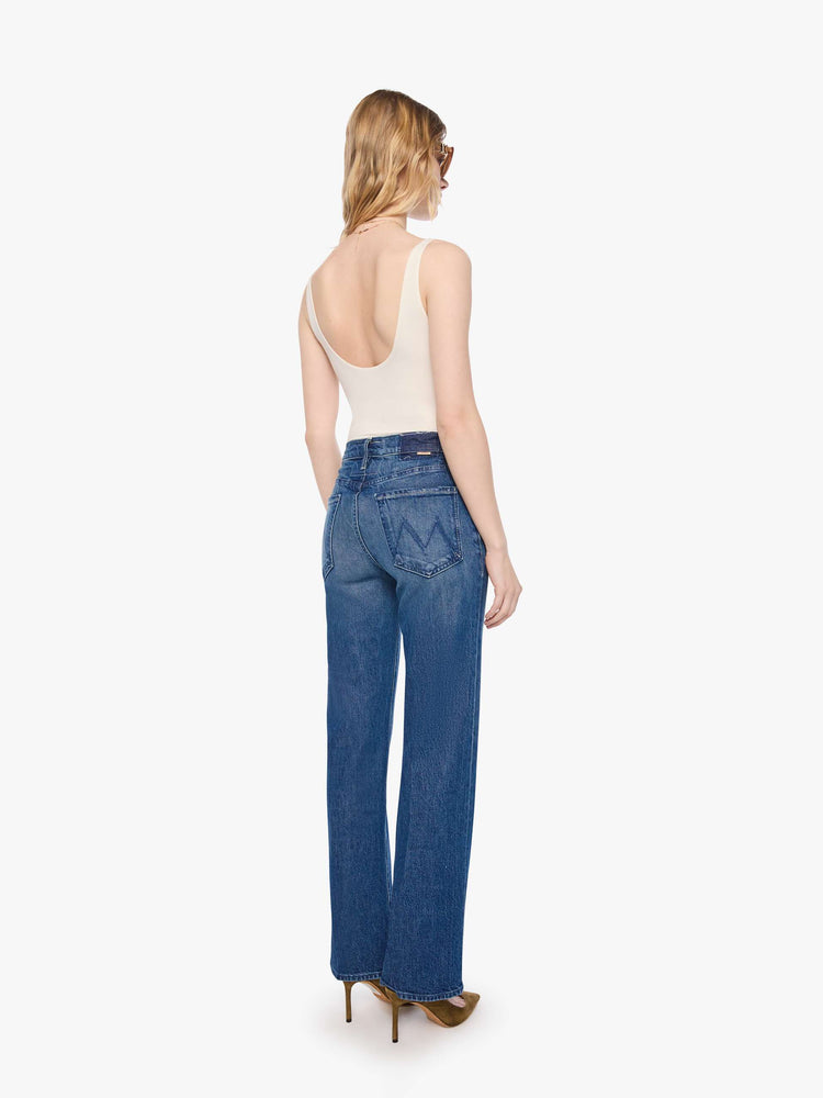 Back view of a petite woman in mid blue high-rise straight leg jean with a zip fly, long 30-inch inseam and a clean hem.