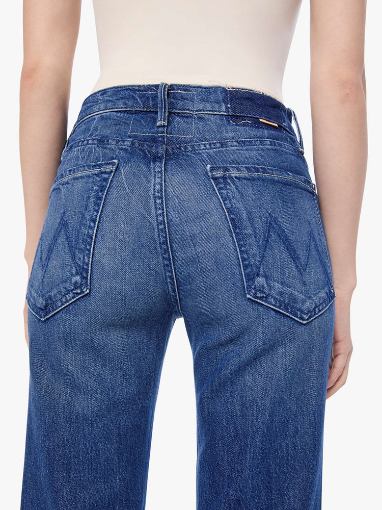 Close up view of a petite woman in mid blue high-rise straight leg jean with a zip fly, long 30-inch inseam and a clean hem.