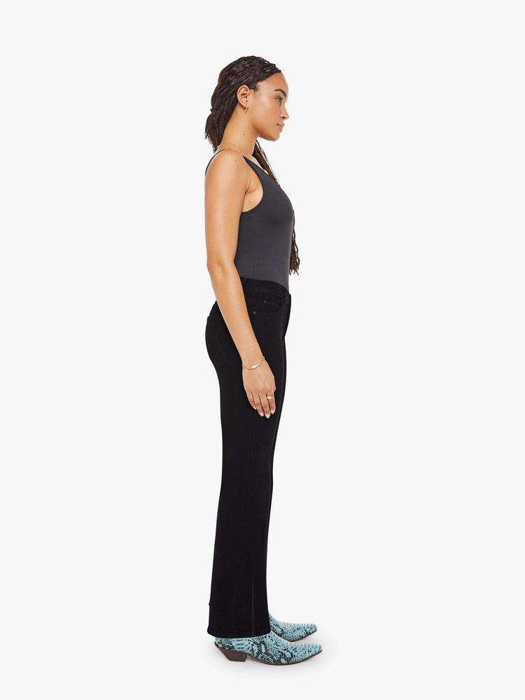 Side view of a woman in a black high-rise straight leg jean with a 30-inch inseam and a clean hem.