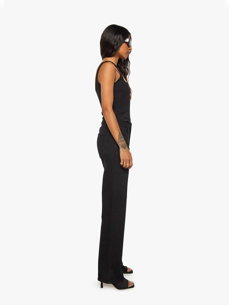 Side view of a woman in a black high-rise straight leg jean with a 30-inch inseam and a clean hem.