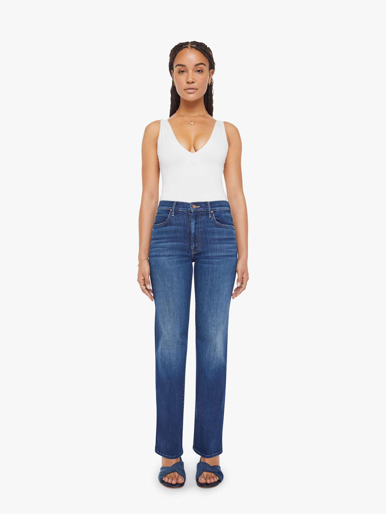 Front view of a petite woman in a med blue high-rise straight leg jean with a zip fly, 31.25-inch inseam and a clean hem.