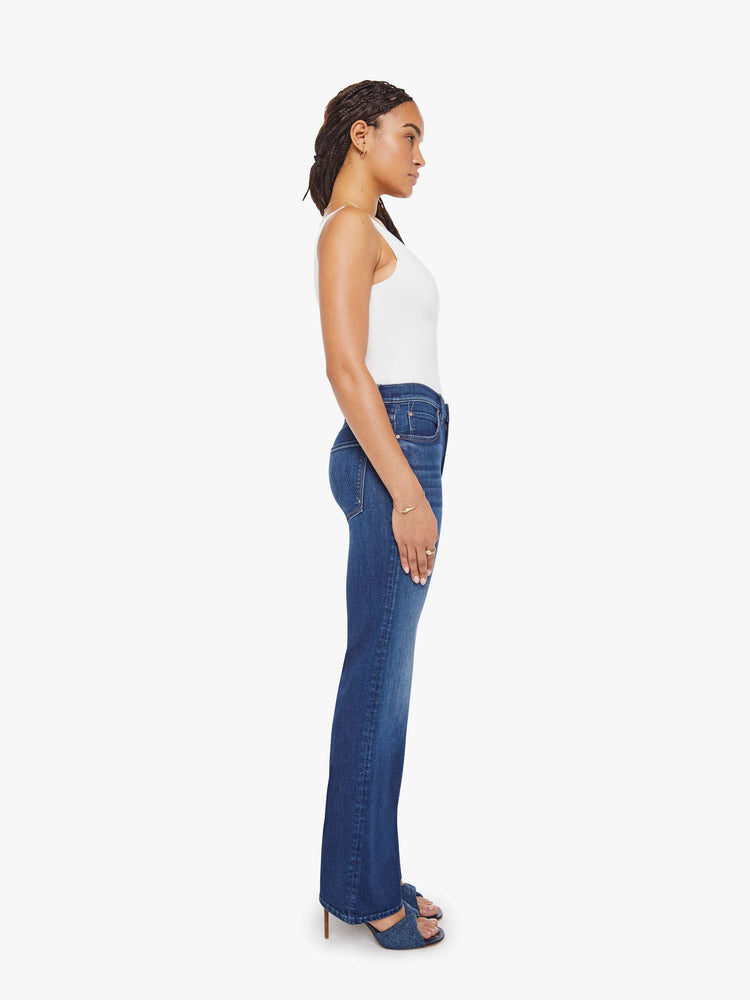 Side view of a petite woman in a med blue high-rise straight leg jean with a zip fly, 31.25-inch inseam and a clean hem.