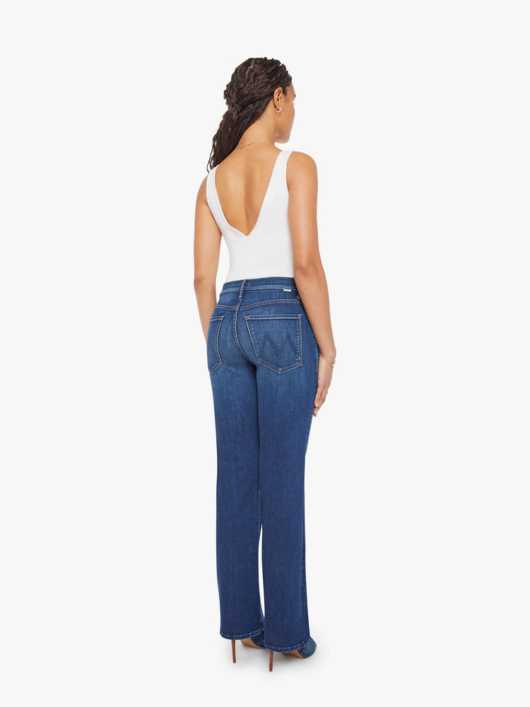 Back view of a petite woman in a med blue high-rise straight leg jean with a zip fly, 31.25-inch inseam and a clean hem.