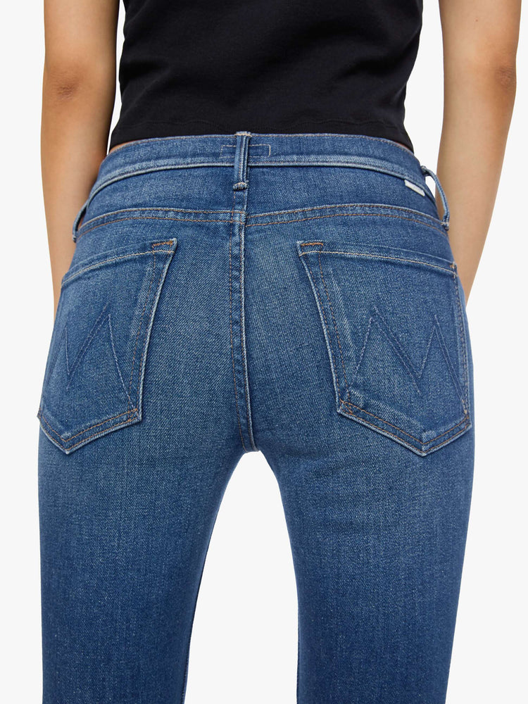 Back close up view of a woman med blue in a skinny flare with a mid rise, zip fly and a long 30-inch inseam with a clean hem.