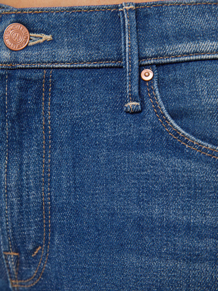 Swatch view of a woman med blue in a skinny flare with a mid rise, zip fly and a long 30-inch inseam with a clean hem.