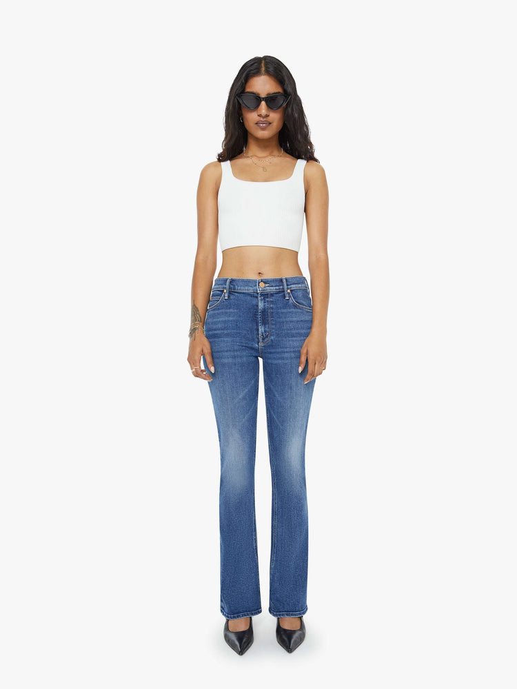 Front view of a petite woman in a med blue  classic skinny flare with a mid rise, zip fly and a long 31-inch inseam with a clean hem. 