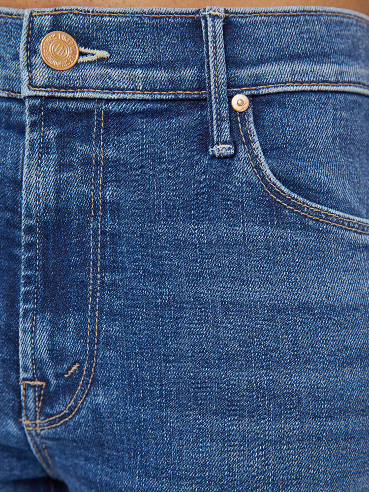 Close up view of a petite woman in a med blue  classic skinny flare with a mid rise, zip fly and a long 31-inch inseam with a clean hem. 