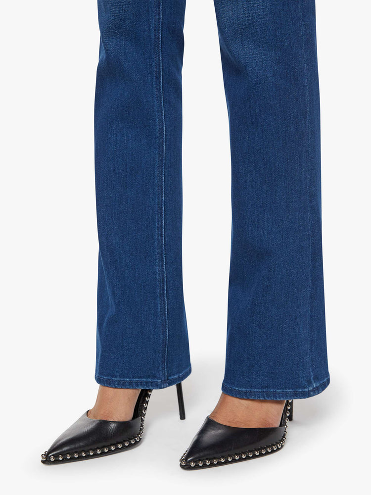 Hem view of a petite woman in a dark blue skinny flare with a mid rise, zip fly and a long 30-inch inseam with a clean hem.