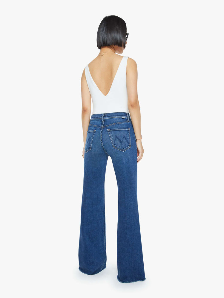 Back view of a mid blue high-rise flare with a long 31-inch inseam and a frayed hem.