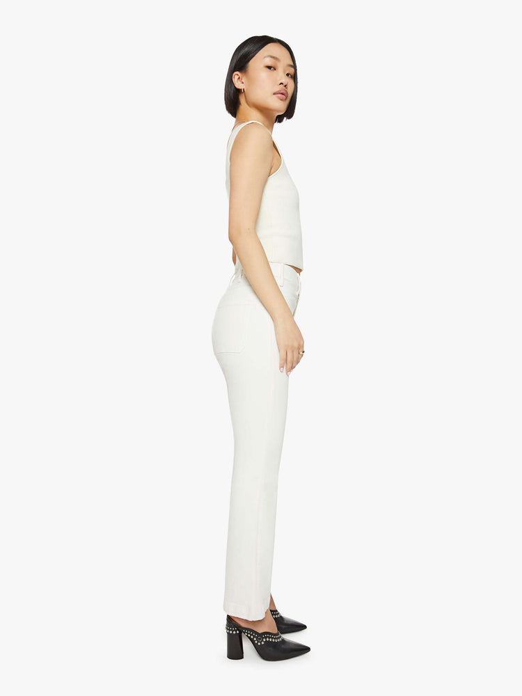 Side  view of a woman off white high-rise bootcut has a cropped inseam, patch pockets and a clean hem.