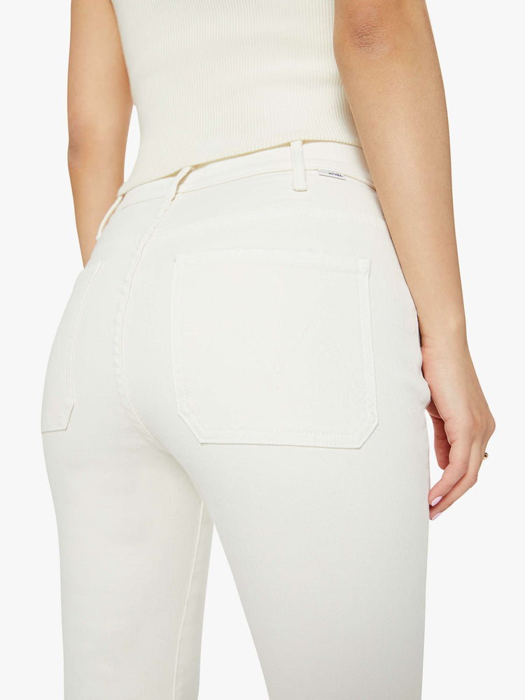 Close up  view of a woman off white high-rise bootcut has a cropped inseam, patch pockets and a clean hem.
