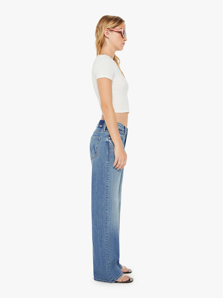 Side view of a womens medium blue wash jean featuring a relaxed mid rise, a wide leg, and clean hem.