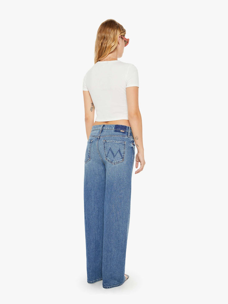 Back view of a womens medium blue wash jean featuring a relaxed mid rise, a wide leg, and clean hem.