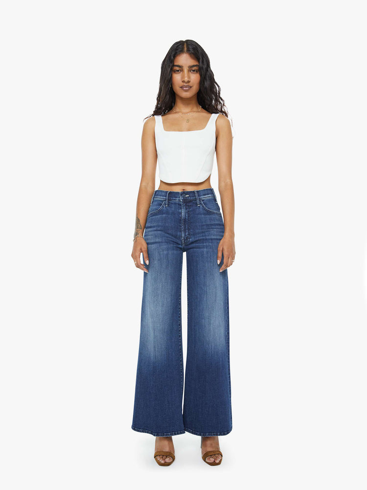 Front view of a petite woman in a dark blue  wide leg jeans have a high rise, zip fly, long 29-inch inseam and a clean hem.