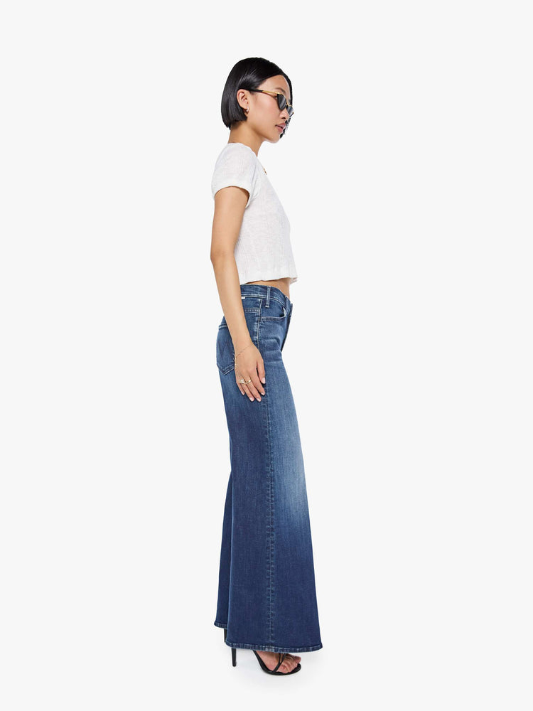 Side view of a petite woman in a dark blue  wide leg jeans have a high rise, zip fly, long 29-inch inseam and a clean hem.