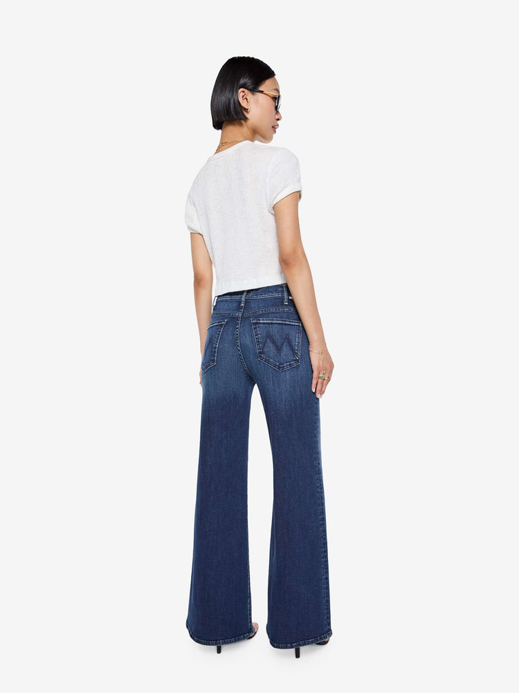 Back view of a petite woman in a dark blue  wide leg jeans have a high rise, zip fly, long 29-inch inseam and a clean hem.
