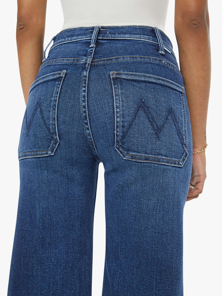 Close up view of a petite woman in a  dark blue wide leg jeans with a high rise, zip fly, patch pockets, 28-inch inseam and a clean hem. 