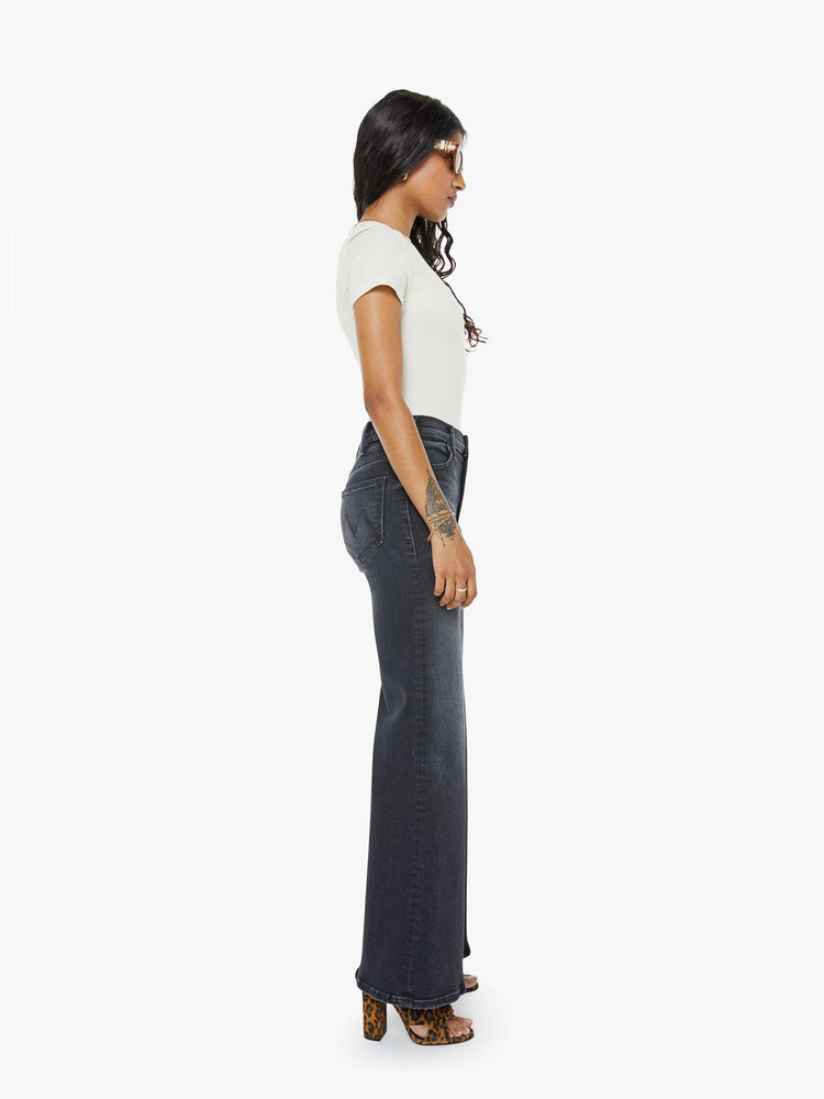 Side view of a petite woman in a black wash  wide leg jeans with a high rise, 30-inch inseam and a clean hem. 