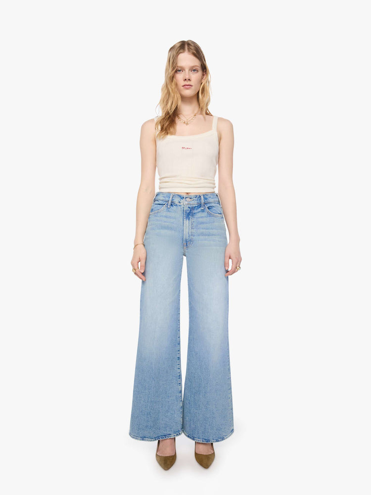 Front view of a petite woman in a light blue wide leg jeans with a high rise, zip fly, 32-inch inseam and a clean hem.