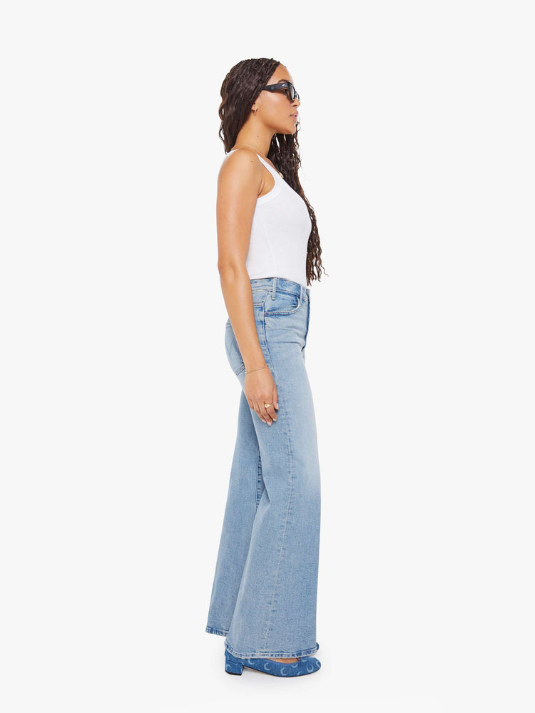 Side view of a petite woman in a light blue wide leg jeans with a high rise, zip fly, 32-inch inseam and a clean hem.